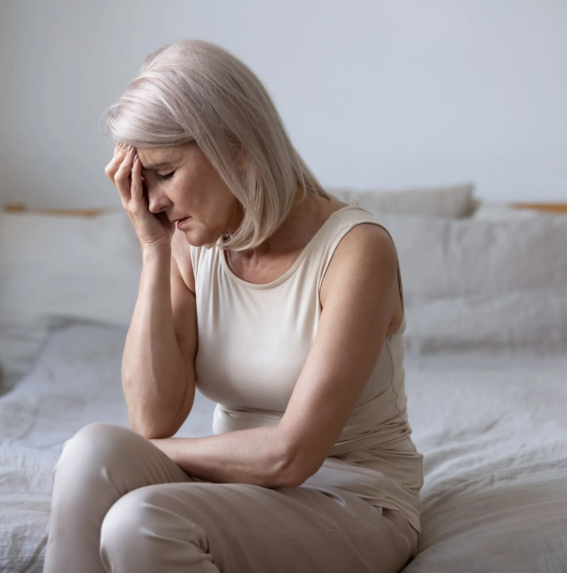 A menopausal woman sitting on her bed reflecting