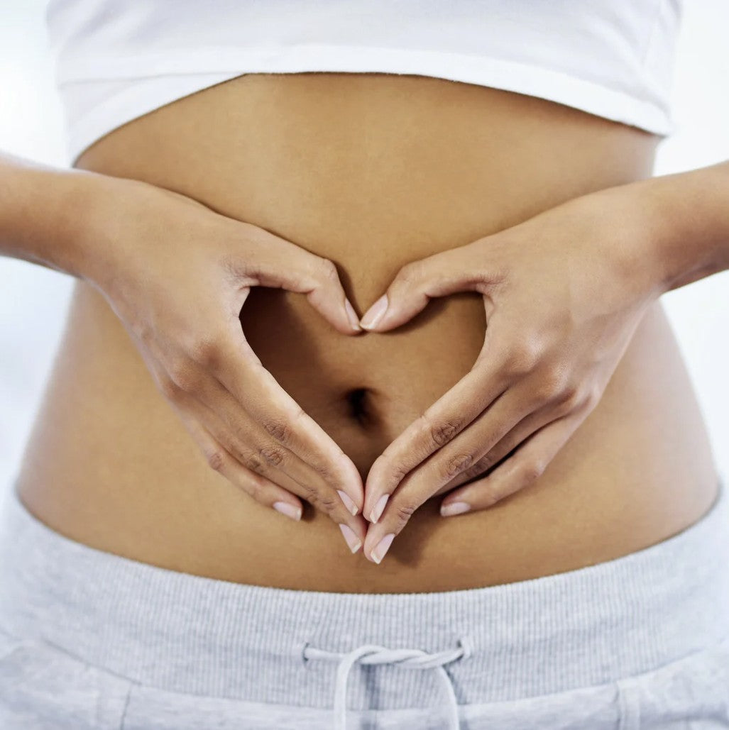 A woman making a love heart with her hands over her stomach