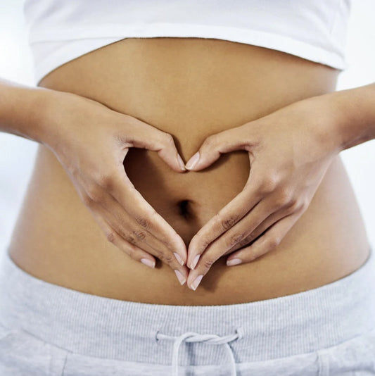 A woman making a love heart with her hands over her stomach
