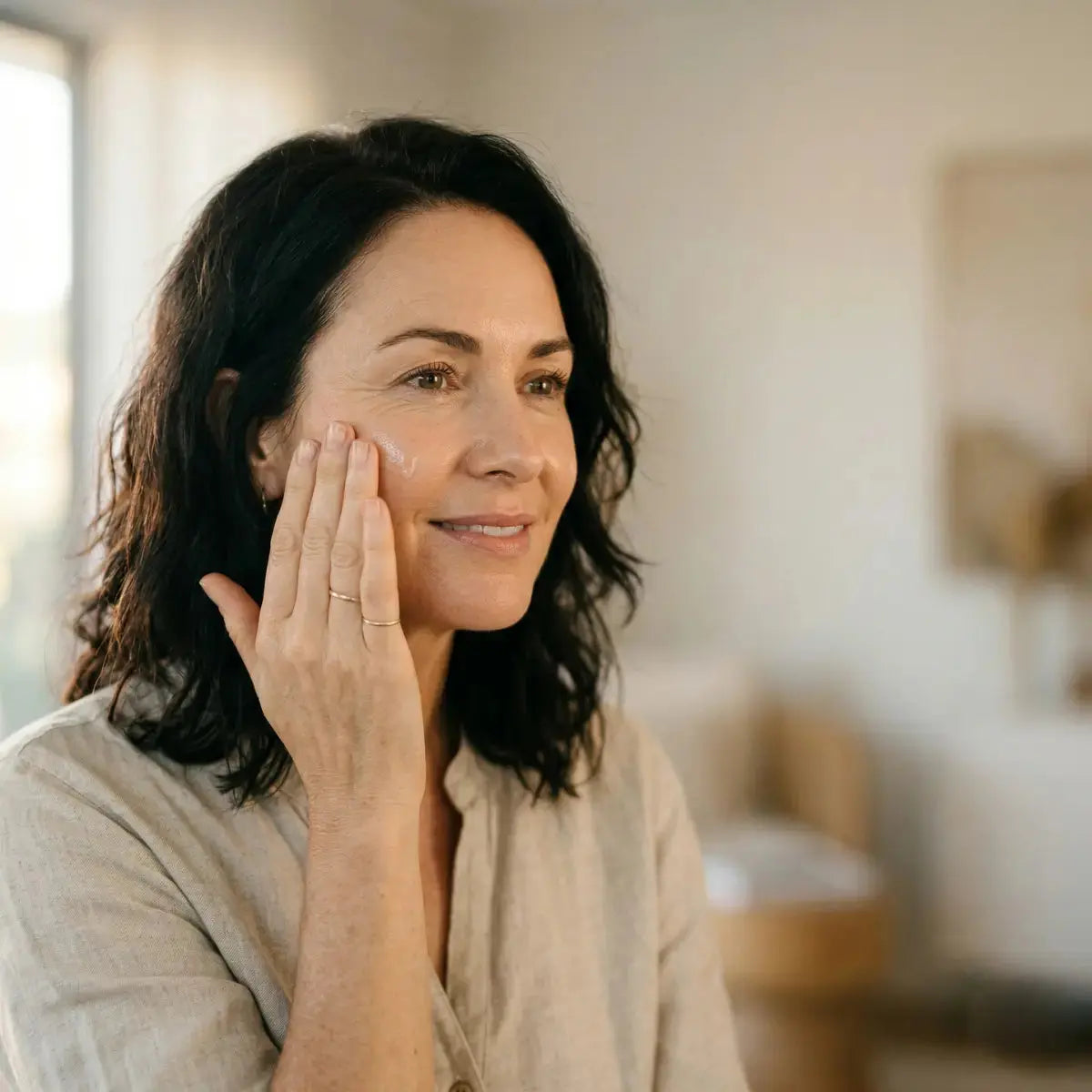 Australian woman in her 50s applying peptide serum to her face as part of a menopausal skincare routine