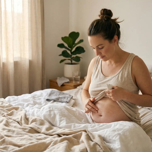 Australian new mum applying silicone scar gel to a healed caesarean scar in natural bedroom light