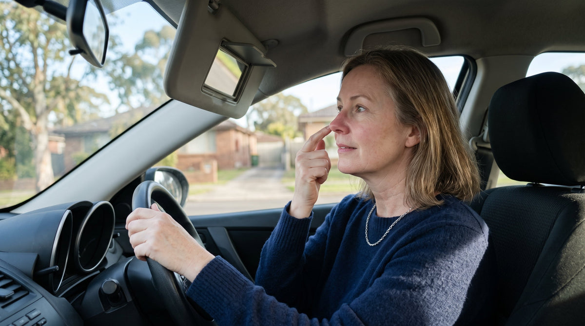 Woman in her fifties checking redness around her nose in a car visor mirror