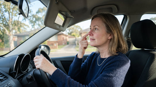 Woman in her fifties checking redness around her nose in a car visor mirror
