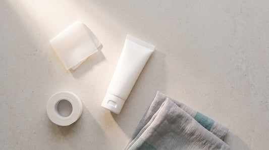Silicone scar gel tube, a silicone sheet and a roll of paper tape laid out on stone, the three formats compared