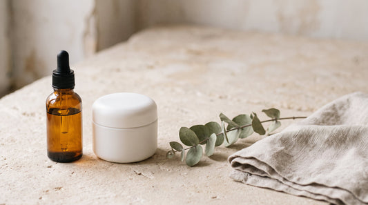 Amber oil bottle beside a white cream jar, comparing stretch mark oil and cream
