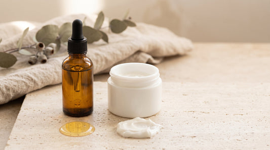 Amber oil bottle beside a white cream jar, comparing stretch mark oil and cream