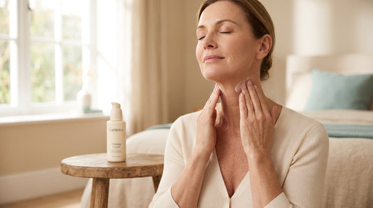 Woman in her fifties smoothing firming cream onto her neck in soft morning light