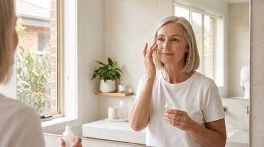 Woman in her fifties applying an anti-wrinkle serum at a bathroom mirror