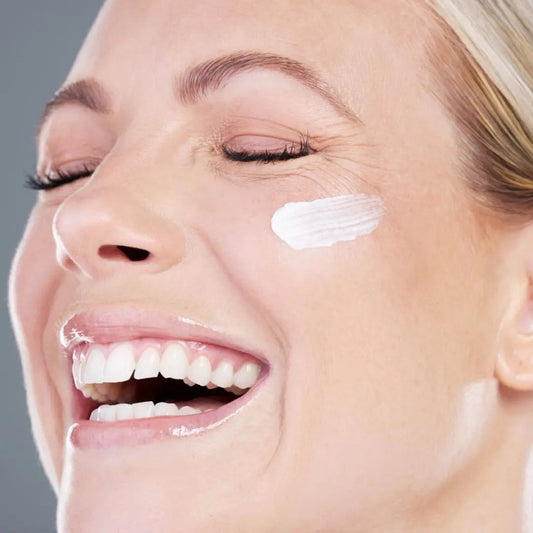 Woman applying face moisturiser as part of a mature-skin routine