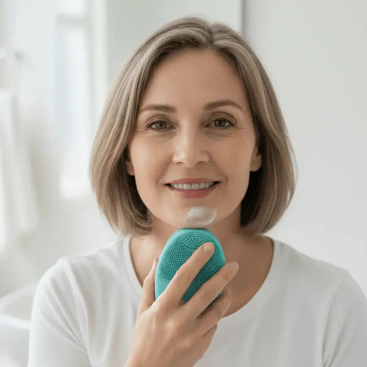 Woman over 50 using a soft silicone cleansing device with cleansing gel as part of a gentle morning face washing routine for menopausal skin