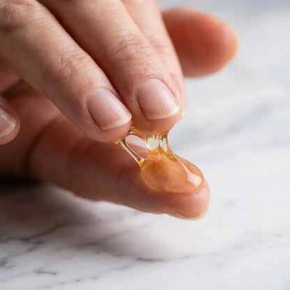 Genova Skincare Cleansing Gel clear golden gel texture between fingertips showing lightweight consistency for pore cleansing